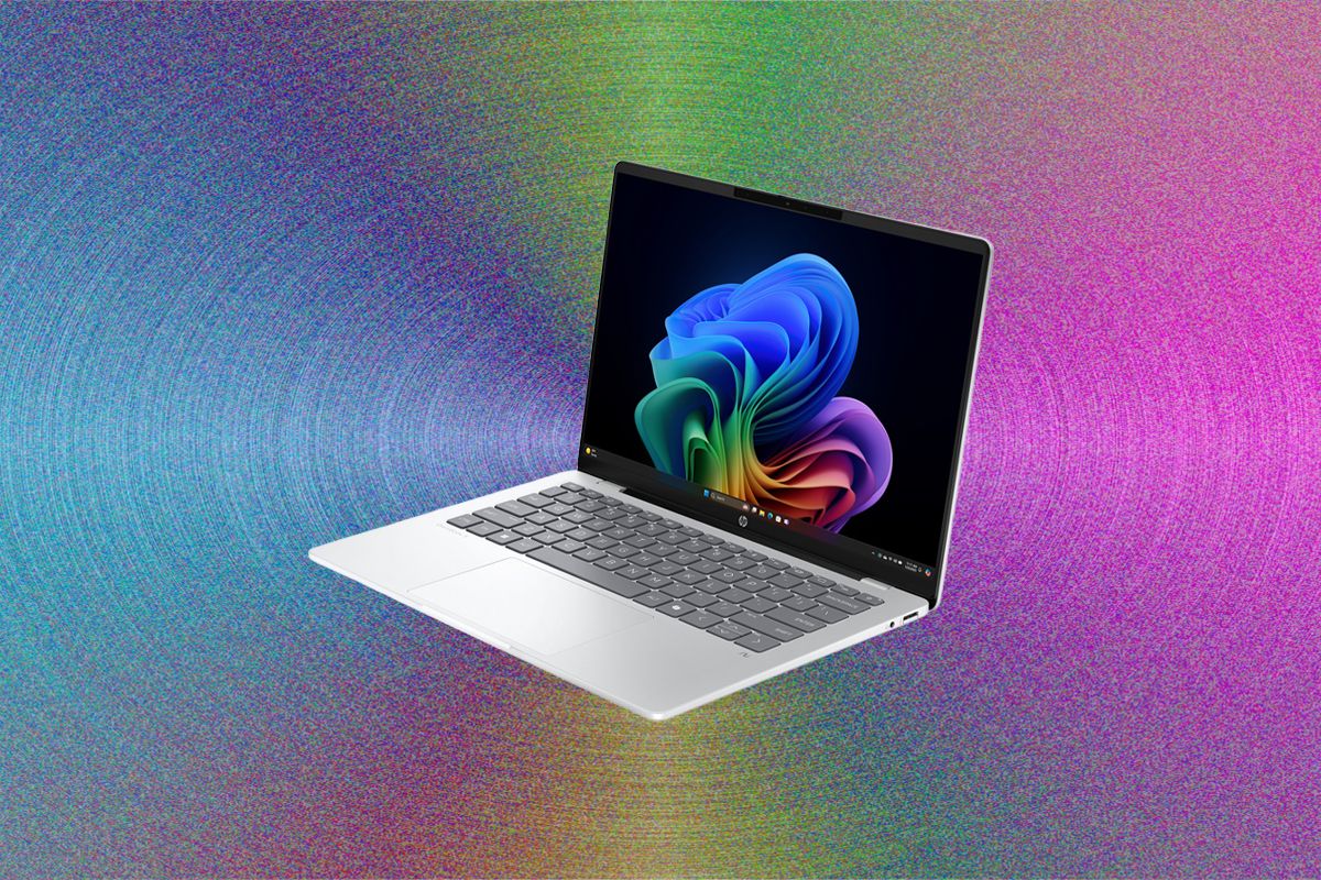 A white laptop with a gray keyboard displaying a colorful blue, green, and pink abstract spiral design on its screen, positioned against a vibrant rainbow-colored textured background.