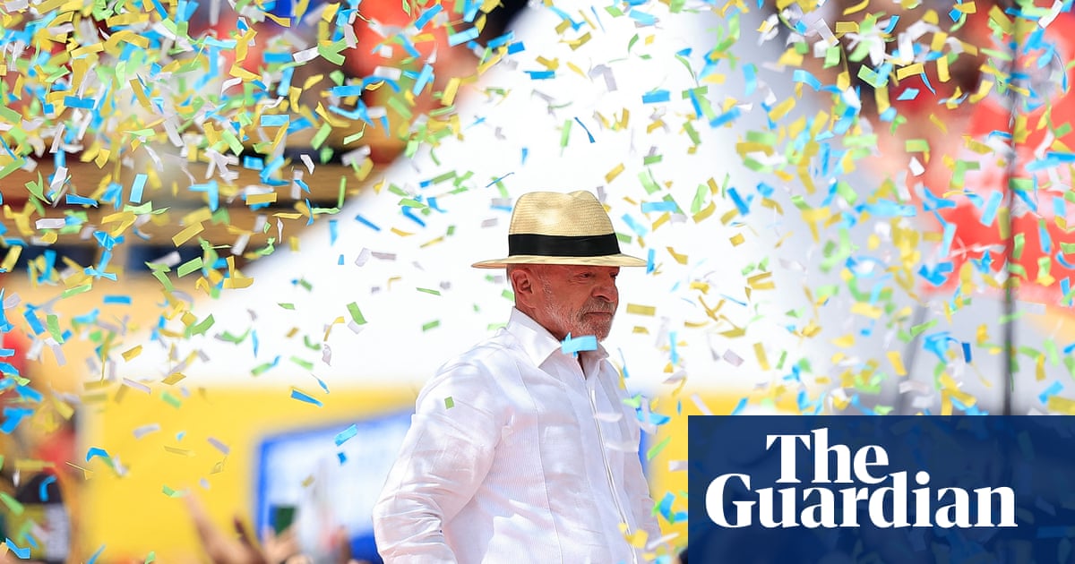 A man wearing a white shirt and straw hat stands in profile amid colorful confetti falling around him.