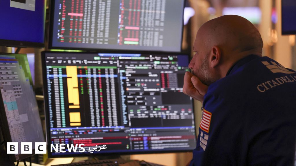 A military officer in uniform carefully observes multiple computer screens displaying complex financial graphs and data in bright colours.