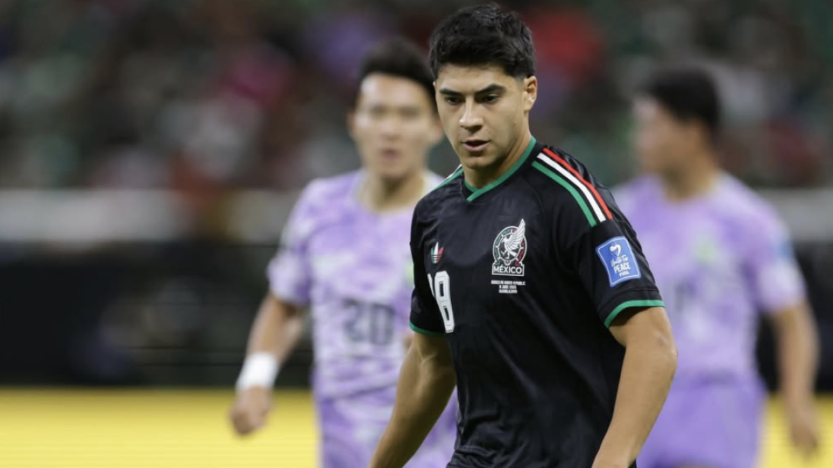 A footballer wearing Mexico's black shirt with number 9, with other players in purple kits blurred in the background during a match.