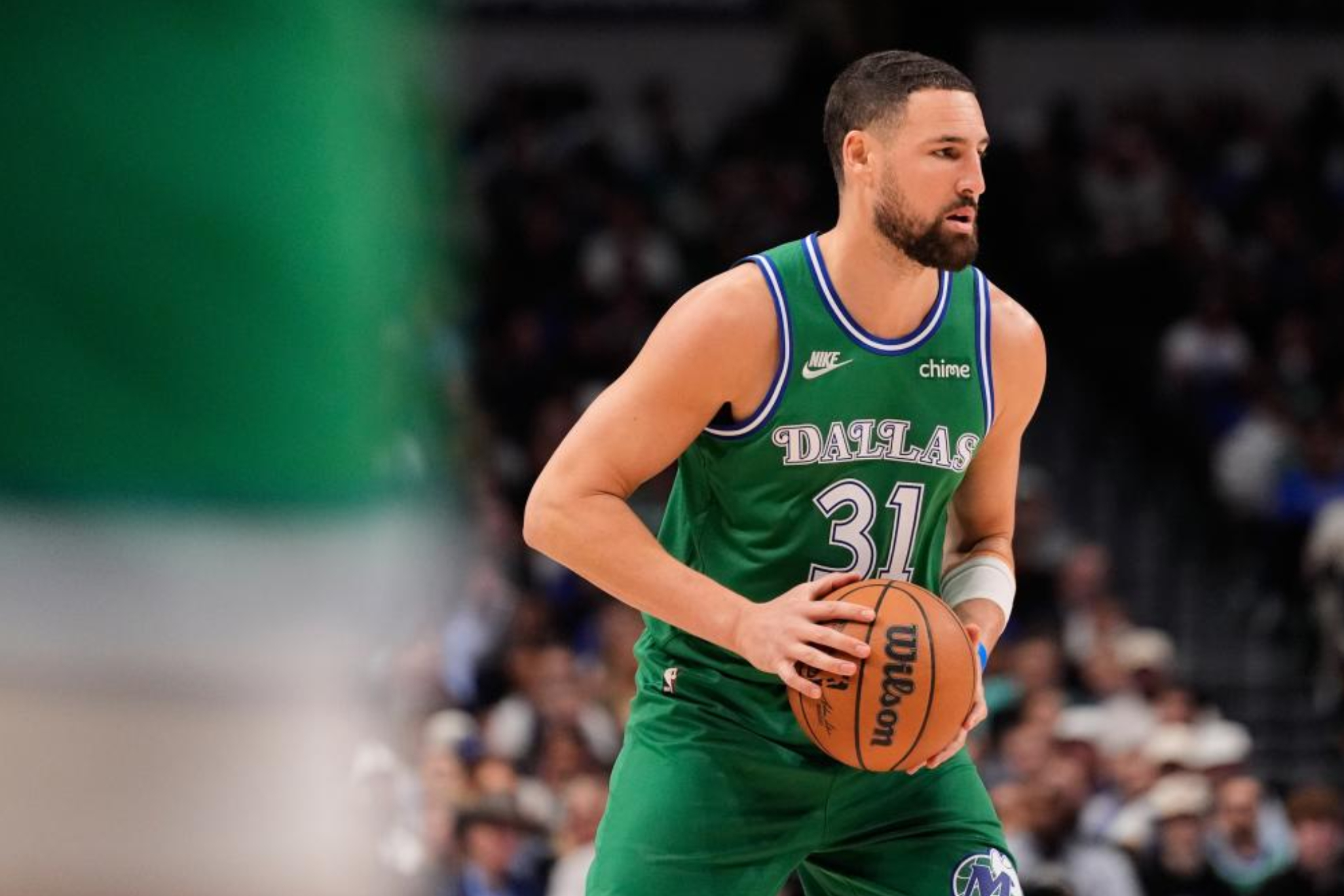 Un jugador de baloncesto profesional vistiendo un uniforme verde de los Dallas Mavericks con el número 31 sostiene un balón durante un partido.