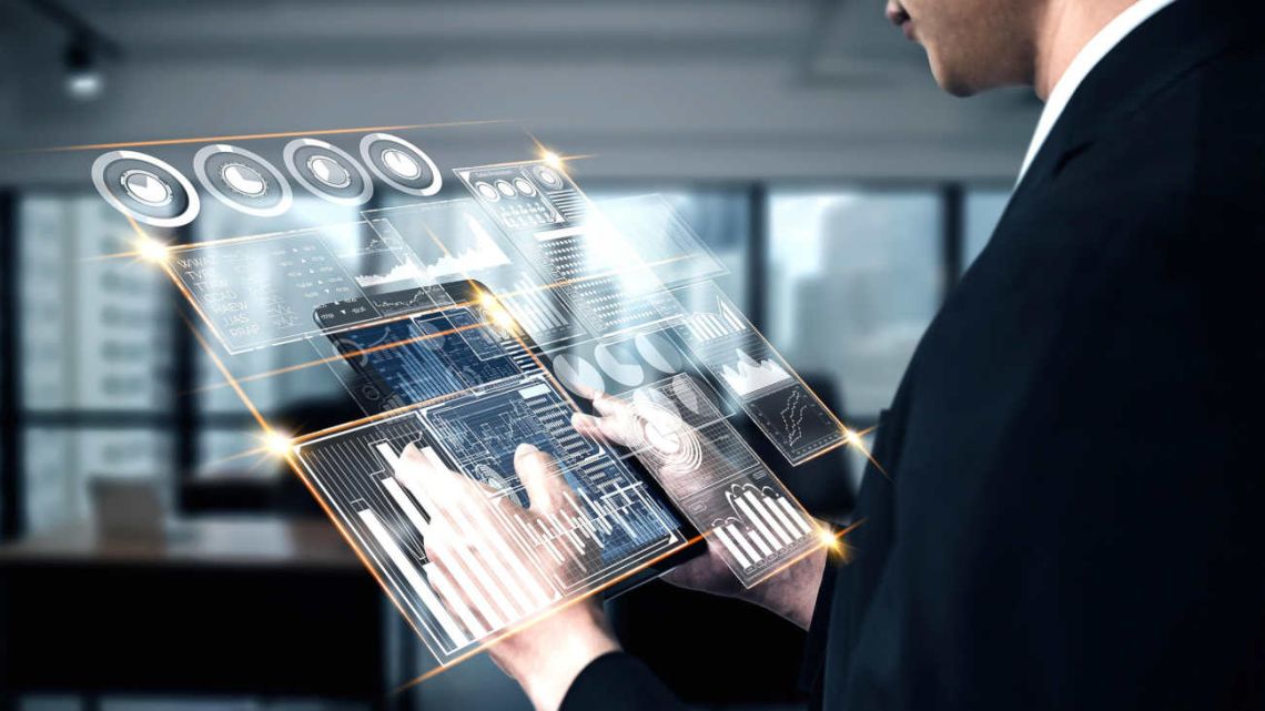 Un empresario en traje oscuro sostiene una pantalla holográfica transparente que muestra gráficos, datos e indicadores de análisis en tonos azules y dorados.