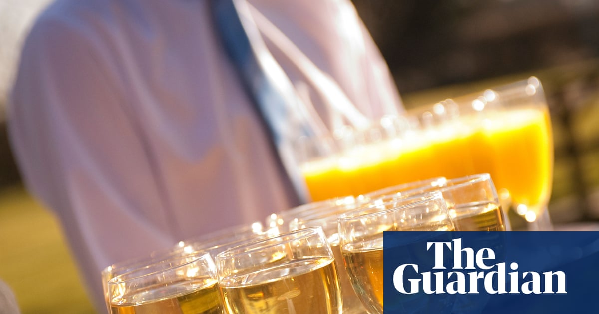 Glasses of beer and a pitcher of orange juice on a table with a person in a purple shirt in the background.