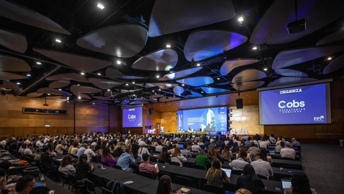 A conference room full of attendees looking towards a main screen where a presentation on municipal decentralisation is projected.