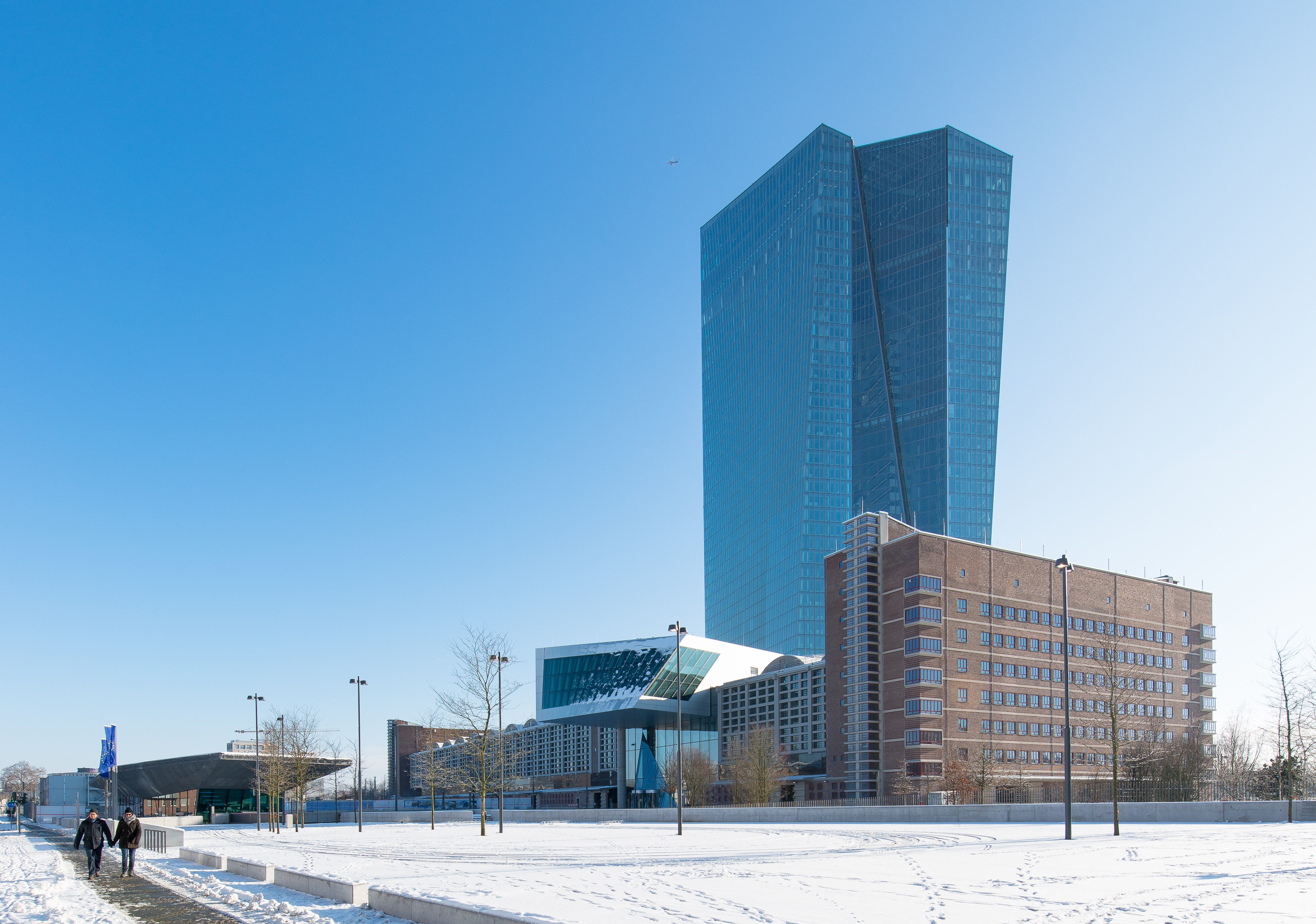 View of Frankfurt's public plaza with modern architecture, including blue glass skyscrapers, red brick buildings and contemporary structures under clear sky with snow on the ground.